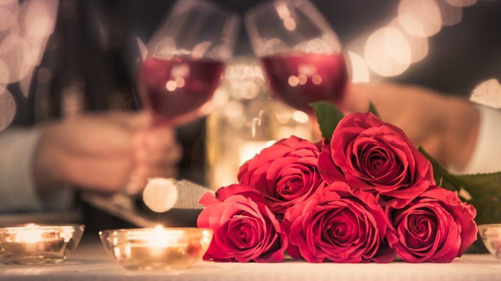 A group of roses and wine glasses on a table